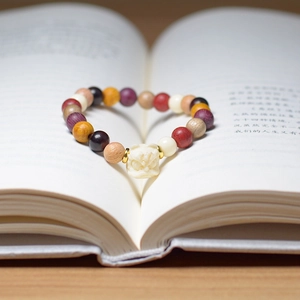 Close-up of multicolored wooden bead bracelet with a carved mythical beast pendant on a book