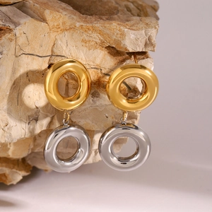 Close-up of gold and silver two-tone double hoop earrings on a textured stone prop