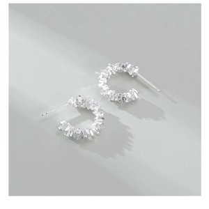 Detail of C-shaped S925 sterling silver earrings with crushed stone texture
