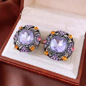 Macro detail of vintage square purple crystal earrings with ornate rhinestone borders