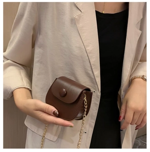 Gros plan d'un mini sac selle en cuir marron avec chaîne dorée et finition mate