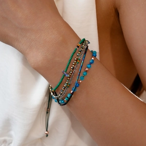 Detail van gelaagde boho-armbanden met turquoise stenen en gevlochten koorden