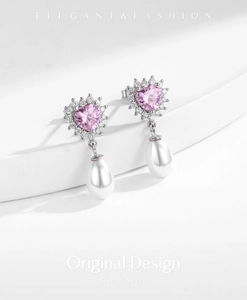 Detail of pink heart zircon earrings with elegant white teardrop pearls on white base