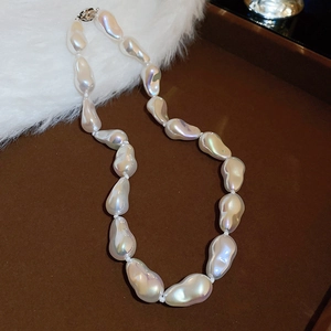 Detail of white baroque pearl necklace with iridescent luster on a dark tray