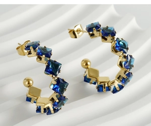 Macro detail of 18K gold-plated C-shaped earrings with square blue zircon stones