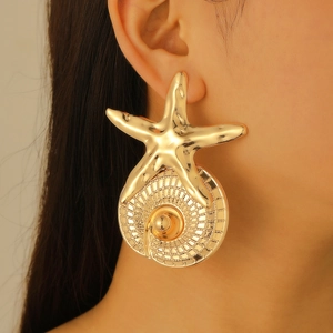 Close-up of oversized gold starfish and conch earrings worn on model for a bold ocean look