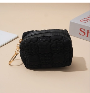 Close-up of black waffle textured mini coin purse with gold zipper and metal keychain