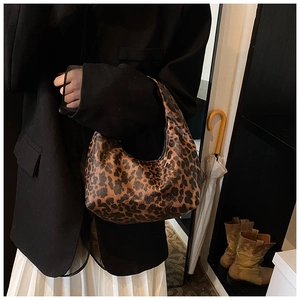 Sac hobo à imprimé léopard porté avec un blazer noir et une jupe plissée blanche chic