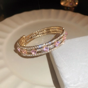 Detail shot of three-row pave zircon bracelet with pink round stones in champagne gold