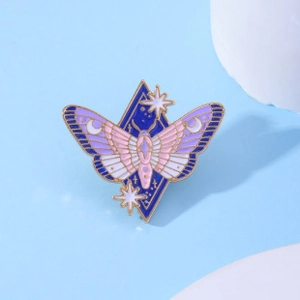 Macro shot of a moth enamel pin with star and moon details on a gold metal base