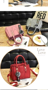 Detailed close-up of textured leather handbag with plush ball pendant and LOVE ribbon detail