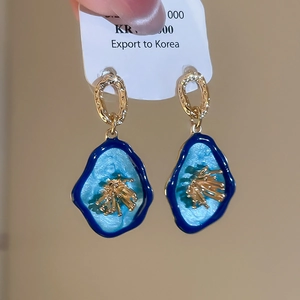 Vue détaillée de boucles d'oreilles florales vintage en or et émail bleu de style rétro