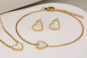 Detail of gold-plated stainless steel jewelry set with white shell heart-shaped charms