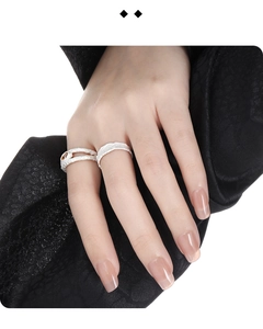 Macro shot of silver textured rings with gemstone inlay on model's hand with black fabric