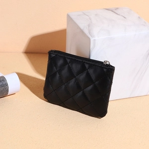 Close-up of black quilted leather coin purse with silver zipper on marble stand