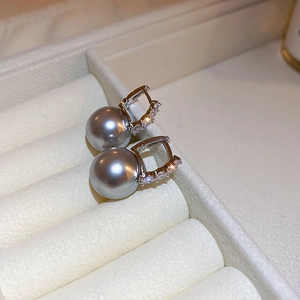 Macro shot of gray pearl earrings with zircon inlay on silver hoops and white velvet