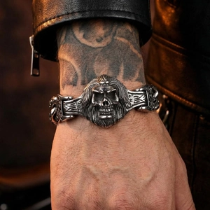 Detail of vintage wolf and skull engraved stainless steel wide bracelet on a male wrist