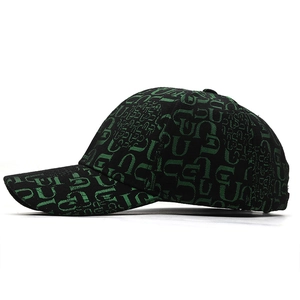 Side view detail of black baseball cap featuring green overlapping letter prints all over