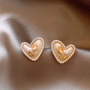 Macro detail of French vintage heart earrings with pearl trim and tulip design