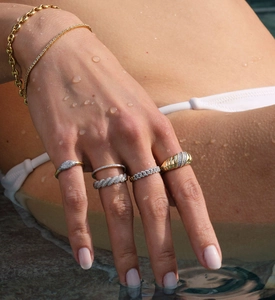 Detail shot of a model wearing sparkling S925 silver twist rings and gold chain bracelets