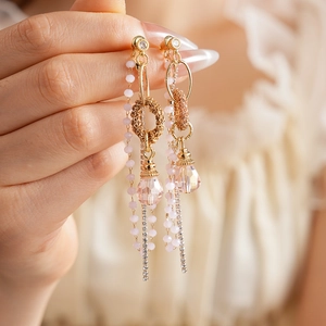 Dettaglio di orecchini vintage dorati con perline rosa e nappe in cristallo scintillante