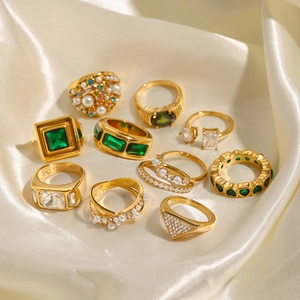 Vintage gold rings with pearls, green emeralds, and zircons on champagne silk fabric
