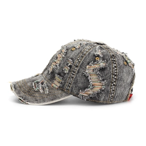 Detailed close-up of distressed denim baseball cap with frayed edges and colorful threads