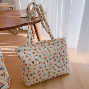 Close-up of cream quilted tote bag featuring retro bear and floral prints and fabric tag