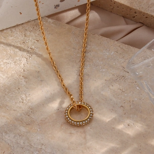 Macro view of golden twisted rope chain and circular pendant set with sparkling zircons