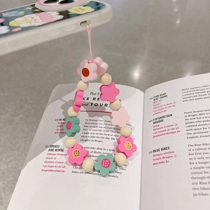 Detail of colorful flower beaded phone strap on an open book with pink wrist lanyard