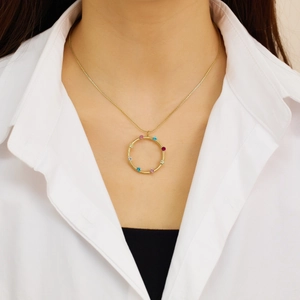 Primer plano de un collar de titanio dorado con colgante de piedras coloridas en una modelo