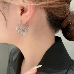 Detailed close-up of silver-tone sunburst hoop earrings with modern metal ray texture