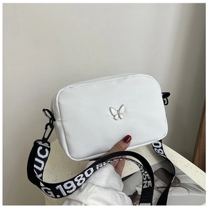 Detailed shot of white nylon square bag with silver butterfly hardware and lettered strap