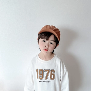 Détail d'enfant portant un t-shirt blanc à manches longues imprimé 1976 et casquette brune