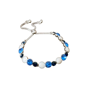 Adjustable silver bracelet with blue and white inlaid diamonds on a white background