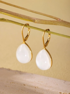 Detailed view of teardrop resin earrings hanging on a twig with a marble base