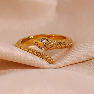 Macro detail of gold snake ring featuring white crystal eyes and realistic scale textures
