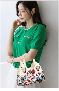 Detail of cream handbag with floral skull print and silver metal hollow handle