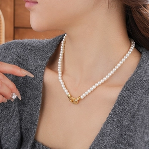 Detail of elegant pearl necklace with gold H-shaped buckle and sparkling zircons
