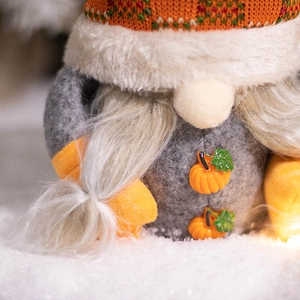 Harvest gnome plush decoration with knitted orange hat and resin pumpkin button on snow