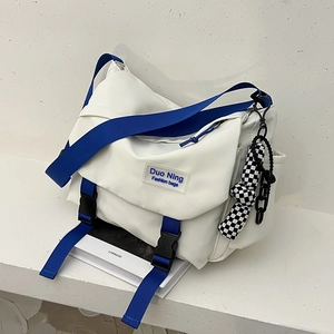 White Japanese-style messenger bag with blue strap and checkerboard keychain charm