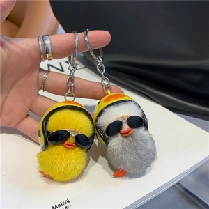 Close-up of cute plush duck keychains in yellow and gray with mini helmets and sunglasses