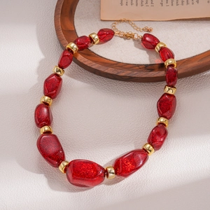 Detail of red glitter resin beads and gold spacers on an adjustable sweater necklace