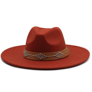 Detail of red wool felt fedora with brown leather band and silver metal studs