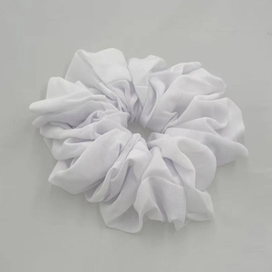 Detailed close-up of white chiffon hair scrunchie with soft pleated fabric texture