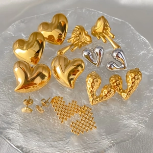 Vue macro de diverses boucles d'oreilles cœur en or et argent sur plateau verre