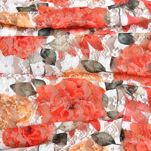 Macro shot of red floral lace fabric with green leaves and white mesh texture details