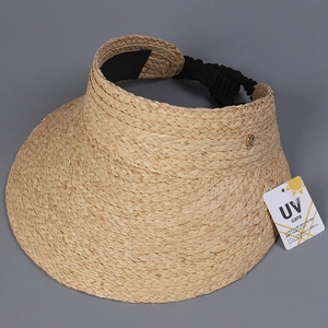 Detail of raffia sun visor hat with UV protection tag and gold metal accent