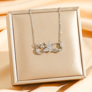 Silver infinity butterfly necklace with zircon diamonds on gold jewelry display stand