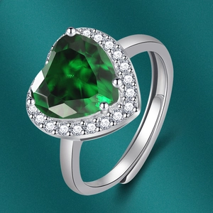 Détail macro d'une bague émeraude en cœur avec halo de diamants et anneau ajustable